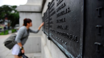 한 관광객이 세계 대전 전사자 기념비에서 전사한 군인들의 비문을 읽고 있습니다.